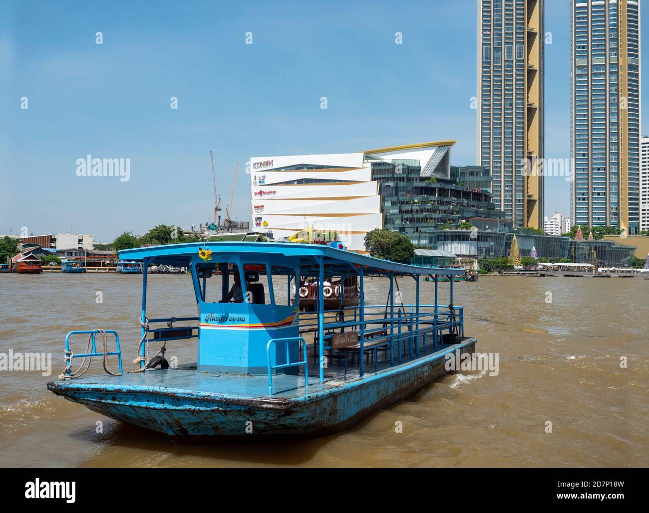 Chao Praya River in Bangkok mit einer Cross River Shuttle Fähre im Vordergrund und Icon Siam Einkaufszentrum und Residenz Türme auf der anderen Seite des Flusses. Stockfoto