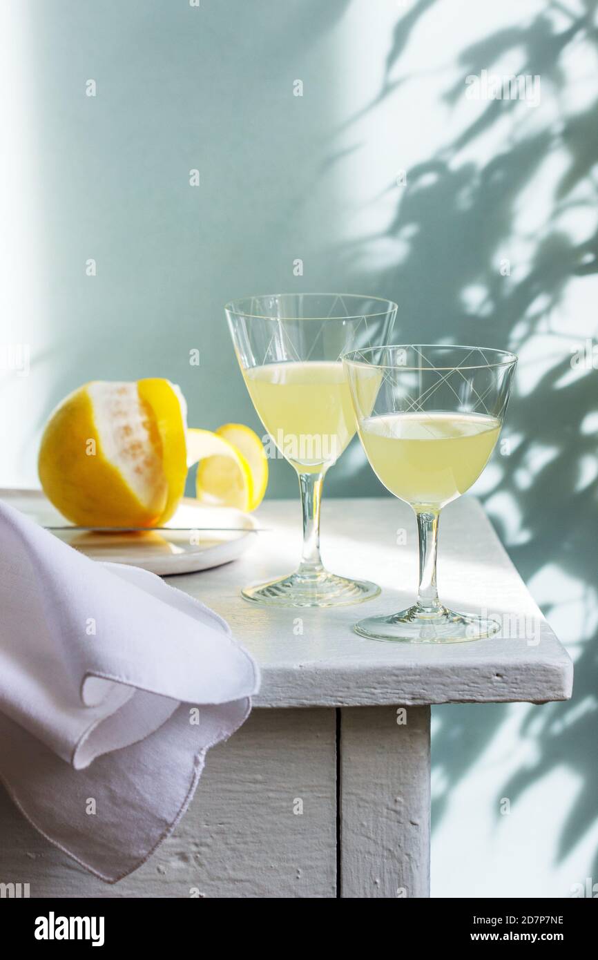 Italienischer Likör Limoncello in Kristallgläsern und reife Zitronen auf einem Holztisch. Stockfoto