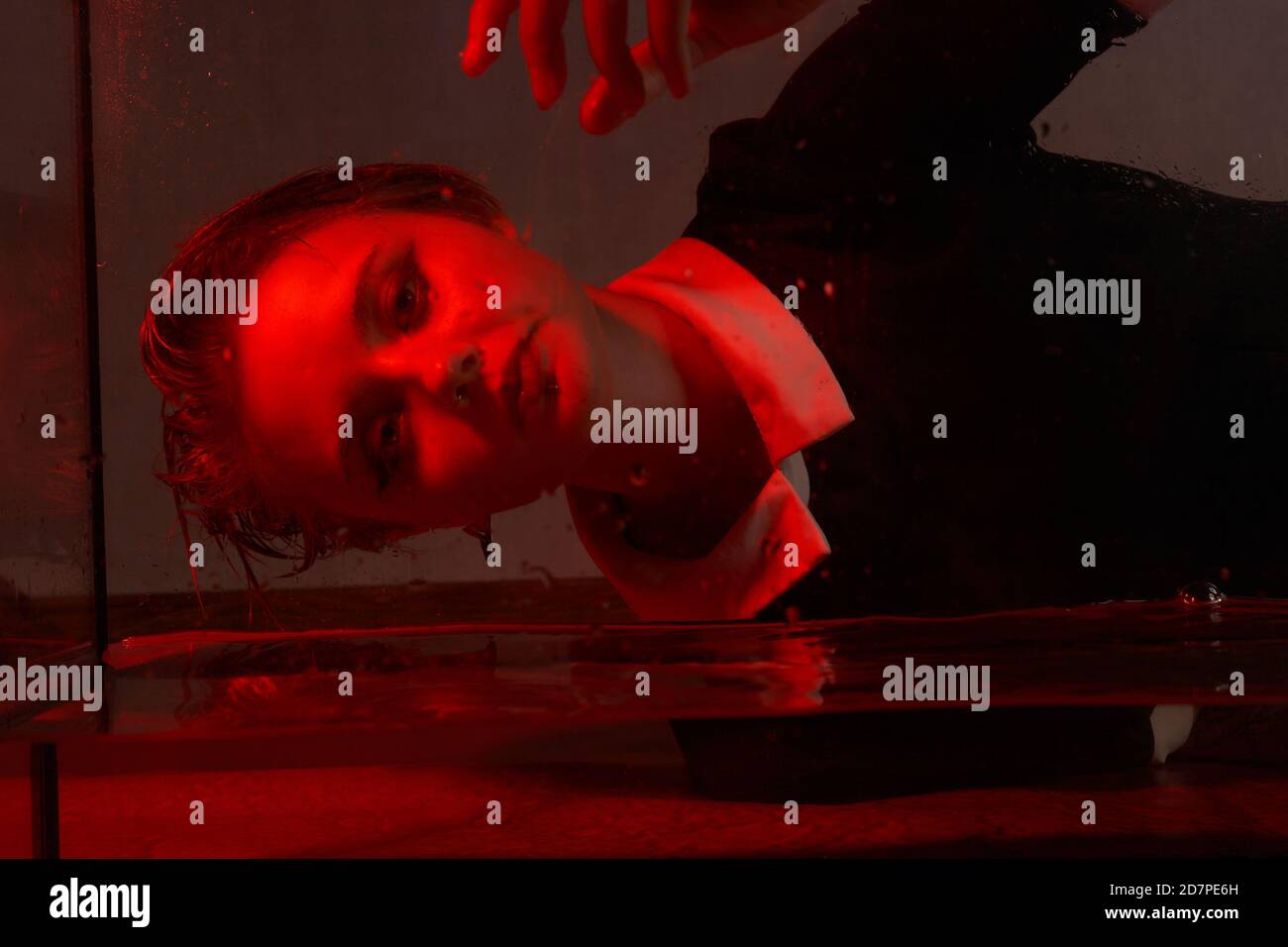 Schreckliches Porträt eines jungen Mädchens in einem Horrorraum mit rotem Licht. Stockfoto