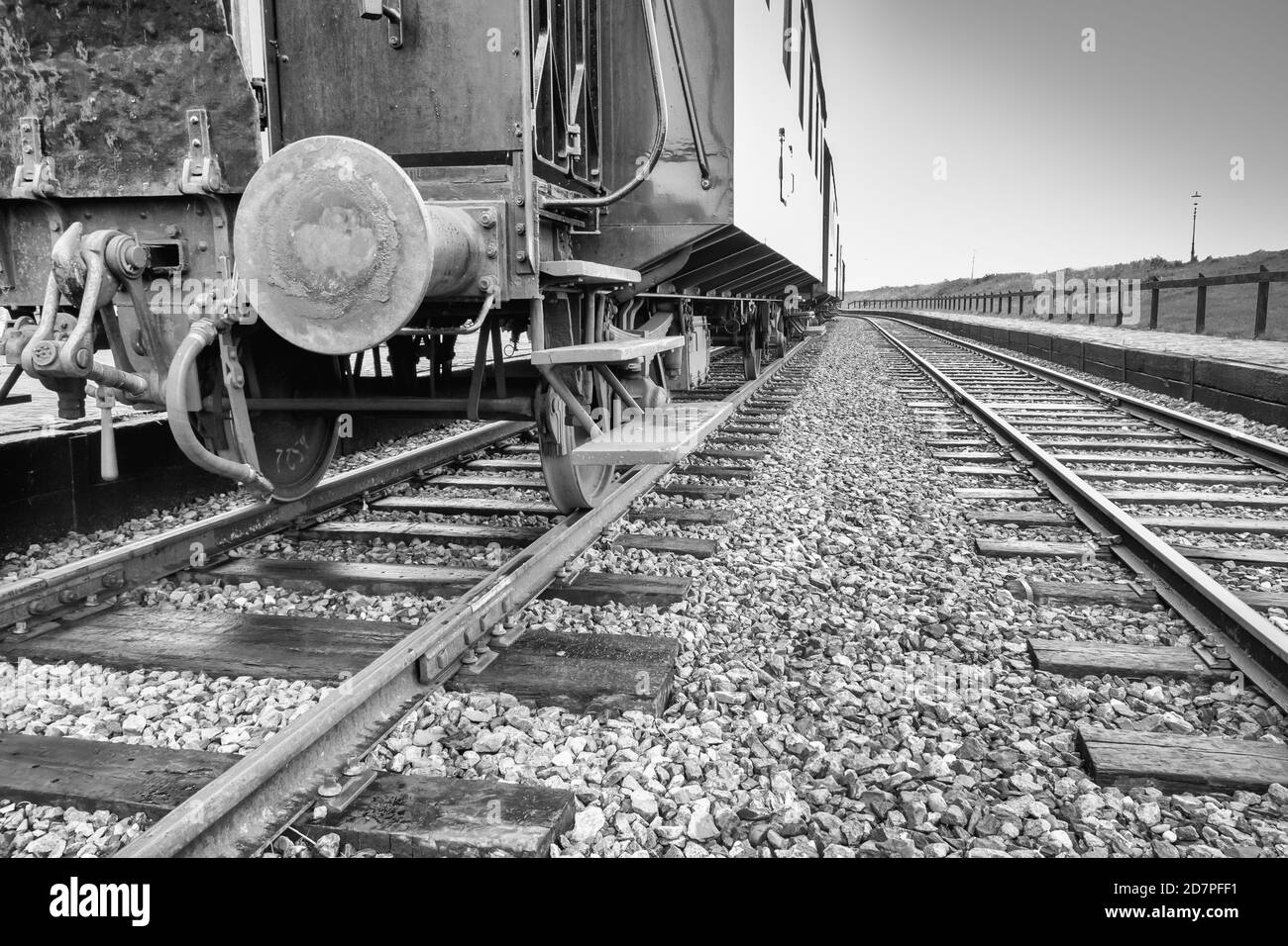 Schwarz-Weiß-Foto von Bahngleisen neben dem Zug auf den Schienen, Aufnahme in Frosch-Position Stockfoto