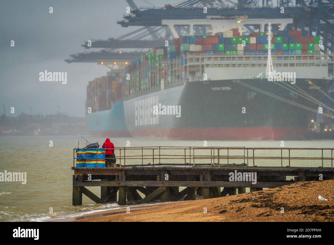 Seefischerei im Regen im Schatten großer Containerschiffe, die im Hafen Felixstowe entladen werden. Hafen von Felixstowe Seefischen. Stockfoto