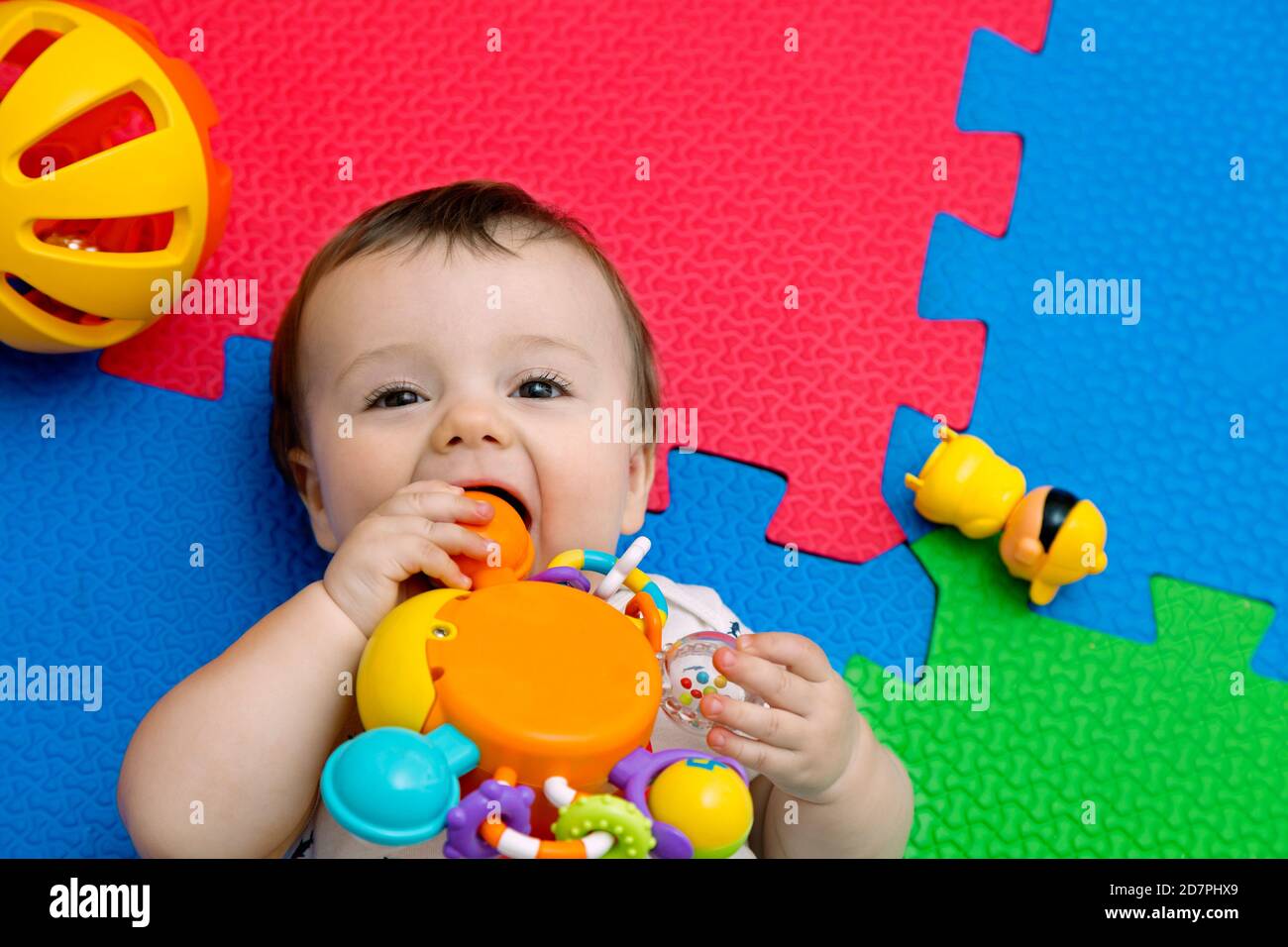 Lustige Baby spielen auf bunten eva Gummiboden. Kleinkind mit Spaß in seinem Haus. Draufsicht. Speicherplatz kopieren. Stockfoto