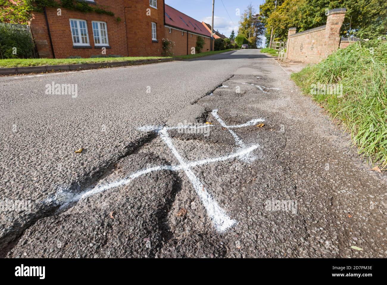 Schlagloch, Pot Holes in UK Landstraße für die Autobahnwartung markiert Stockfoto