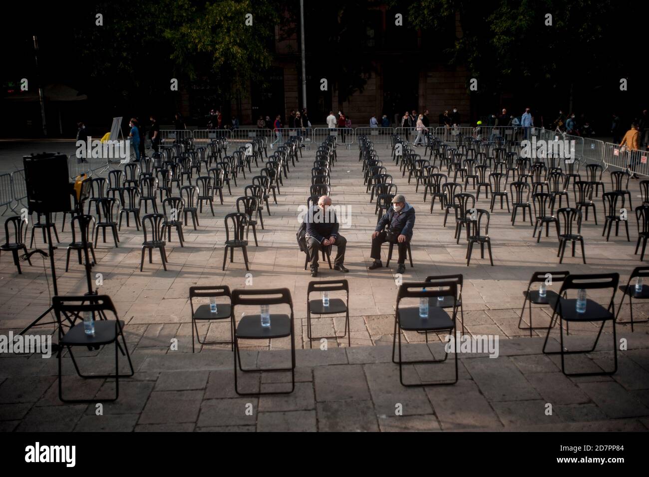 Barcelona, Spanien. Okt. 2020. Zwei Männer mit Schutzmasken sitzen auf Stühlen mit sozialer Distanzierung, um ein Open-Air-Konzert im Zentrum von Barcelona zu veranstalten. Spanien Gerät in einen weiteren Alarmzustand, nachdem acht Regionen die Regierung aufgefordert haben, die Notfallmaßnahme umzusetzen, um Coronavirus-Infektionen einzudämmen. Quelle: Jordi Boixareu/Alamy Live News Stockfoto