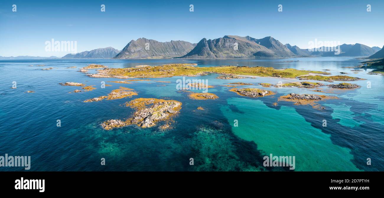 Luftbild, Schärengarten mit Gras, türkisfarbenes Meer, steile Berge im Hintergrund, Lofoten, Nordland, Norwegen Stockfoto