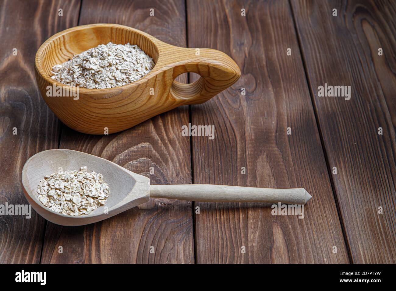 Holzbecher und Löffel mit Haferflocken. Gesunde Lebensmittel. Holzstruktur Stockfoto