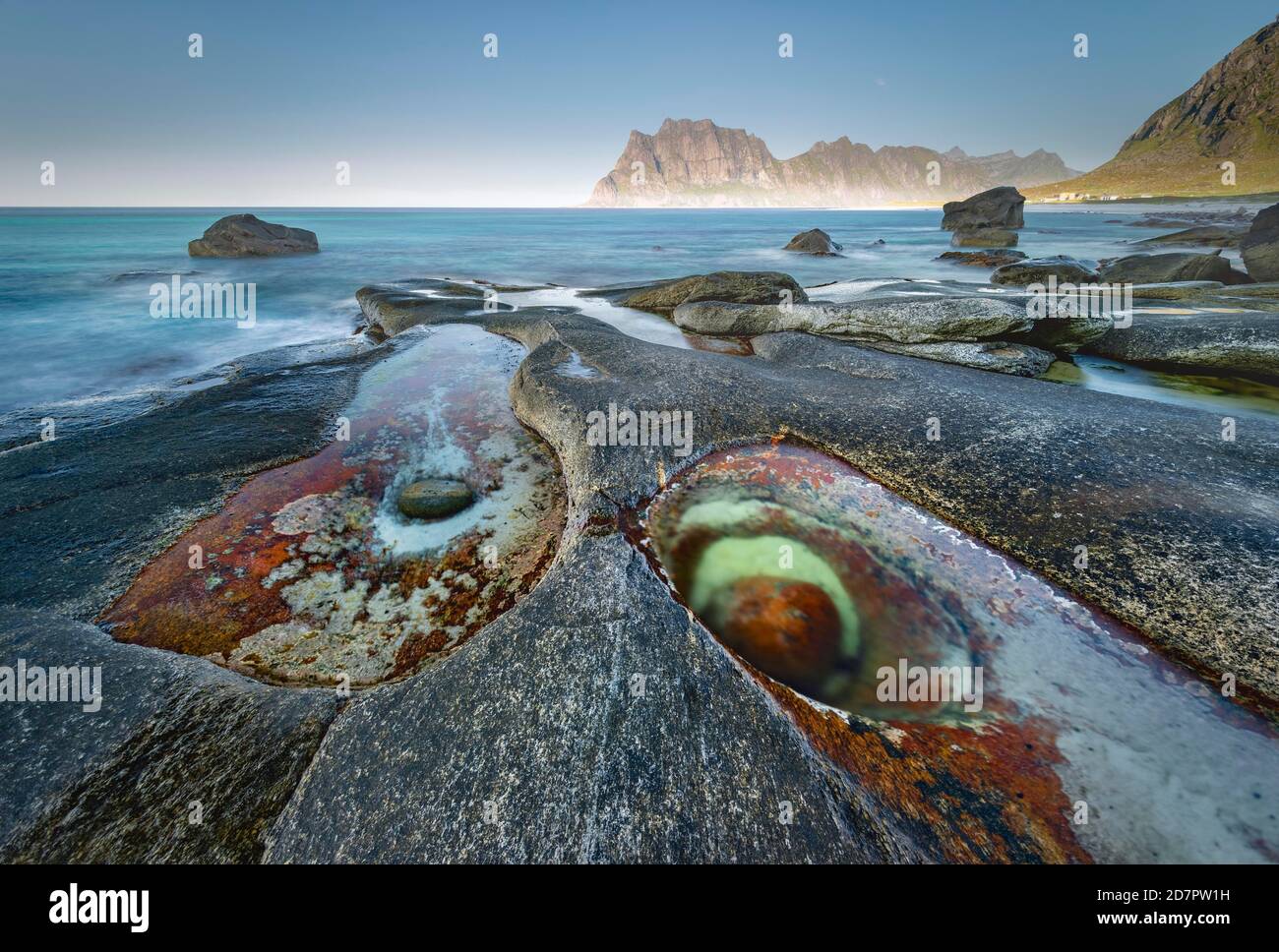 Felsen am Strand, vor Gezeitenbecken mit Formation Eye of Utakleiv, Nordland, Lofoten, Norwegen Stockfoto