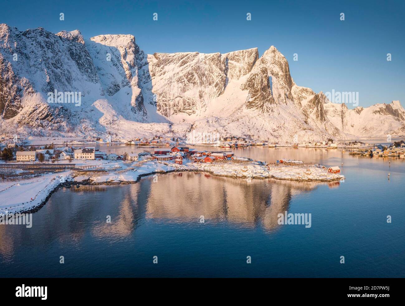 Luftaufnahme, Fjordlandschaft bei Sonnenaufgang, verschneite Berge im Winter, Fischerdorf reine, Nordland, Lofoten, Norwegen Stockfoto