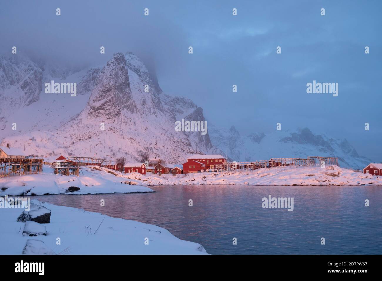 Winterstimmung am frühen Morgen in einem Fischerdorf, Stockfischregale, Schneefall in den Bergen, reine, Nordland, Lofoten, Norwegen Stockfoto