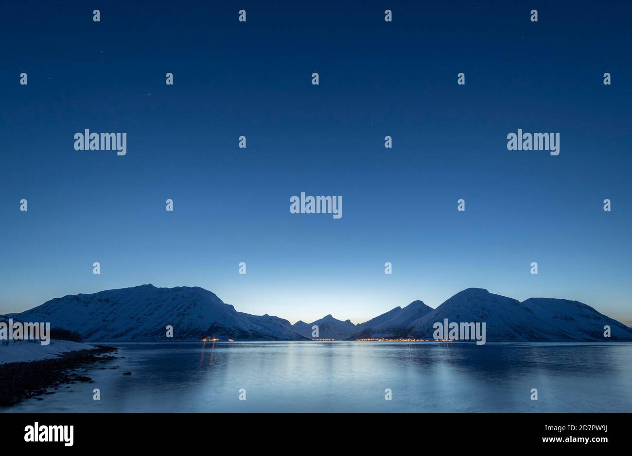 Winter schneebedeckte Bergkette über dem Meer, arktische Winterlandschaft, darüber Nachthimmel mit Sternen Stockfoto