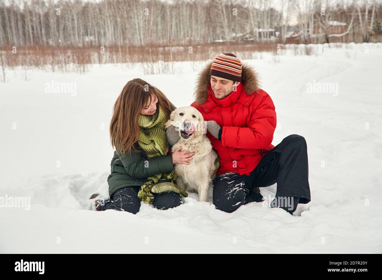 Porträt eines jungen Paares mit Hund auf einem Winterspaziergang. Mann und Frau mit labrador Stockfoto