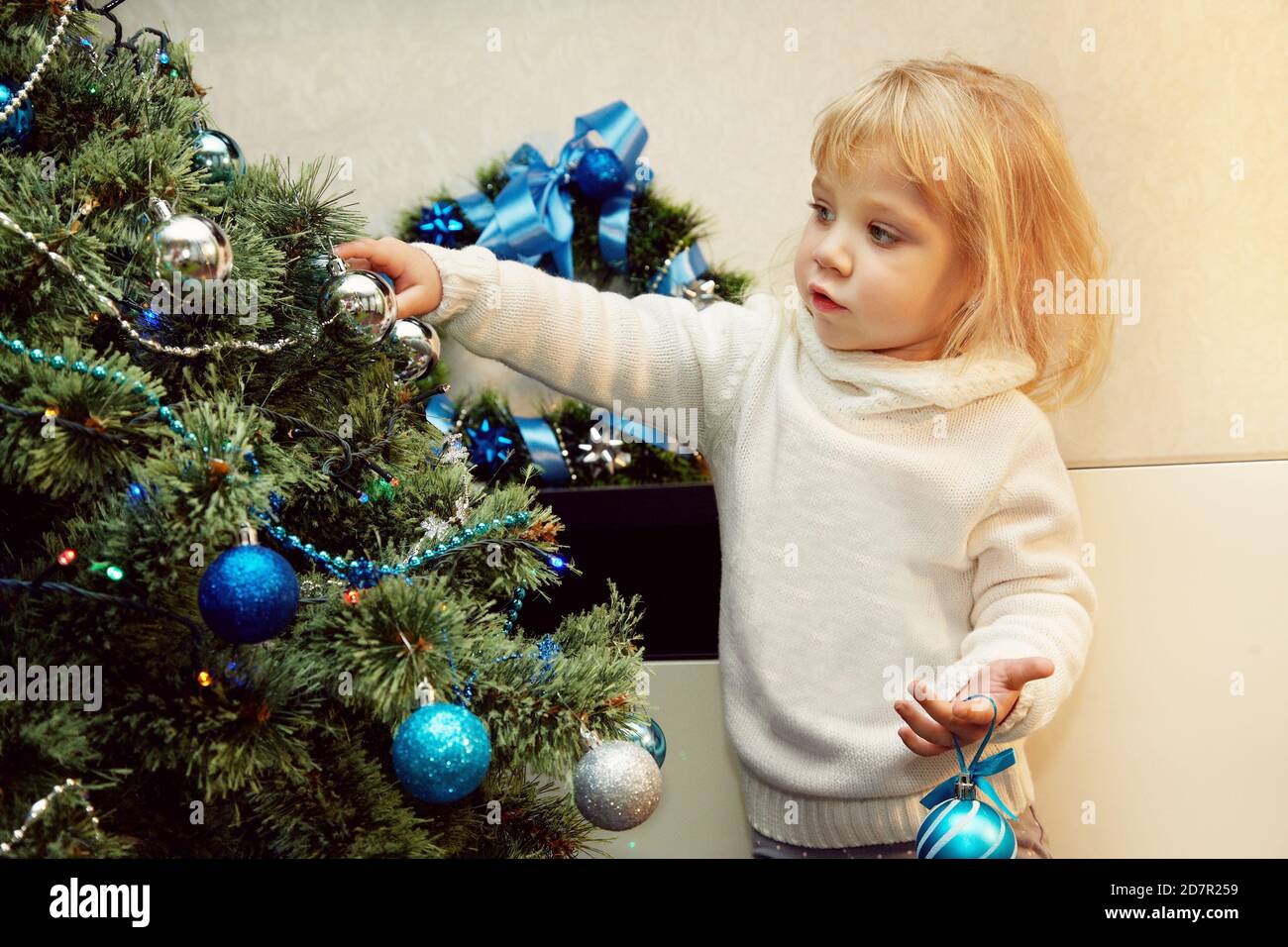 Kleines Mädchen verzieren einen Weihnachtsbaum mit Kugeln Stockfoto
