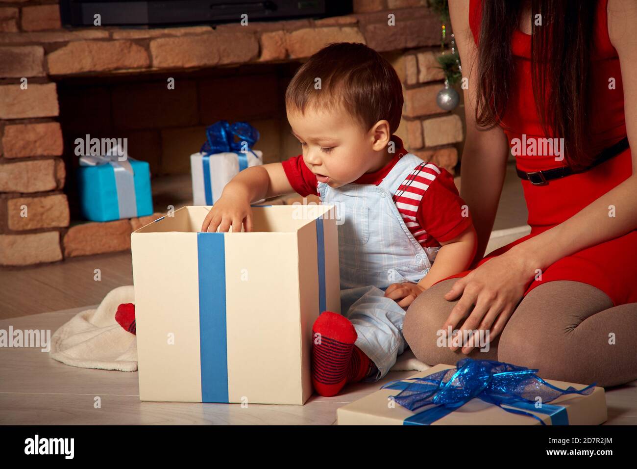 Mutter und Kind zur Weihnachtszeit. Mama gibt Baby ein Geschenk. Neujahr und Weihnachten Menschen Stockfoto