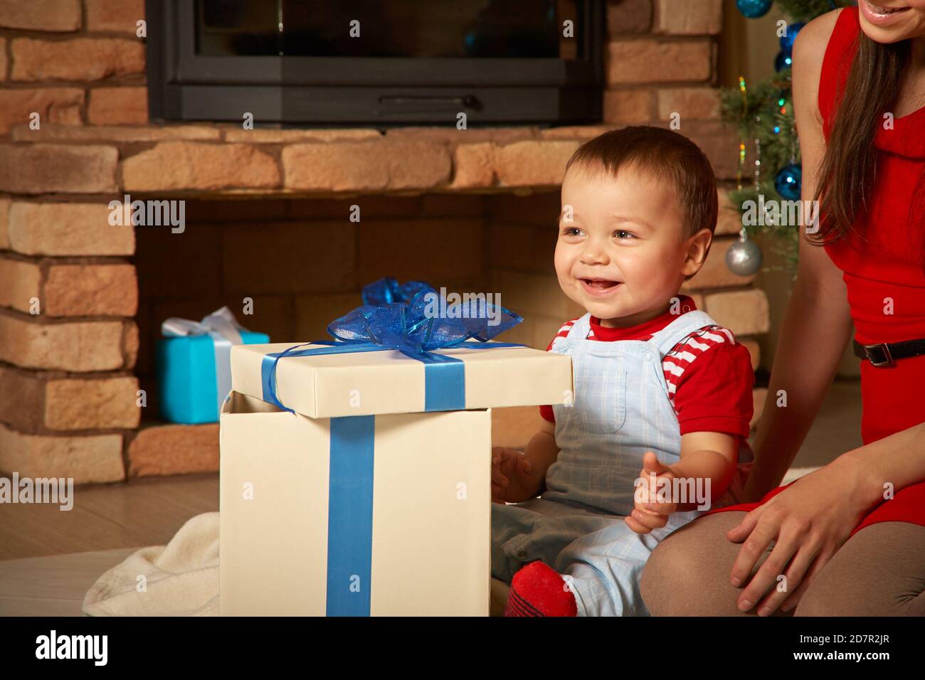 Mutter und Kind zur Weihnachtszeit. Mama gibt Baby ein Geschenk. Neujahr und Weihnachten Menschen Stockfoto