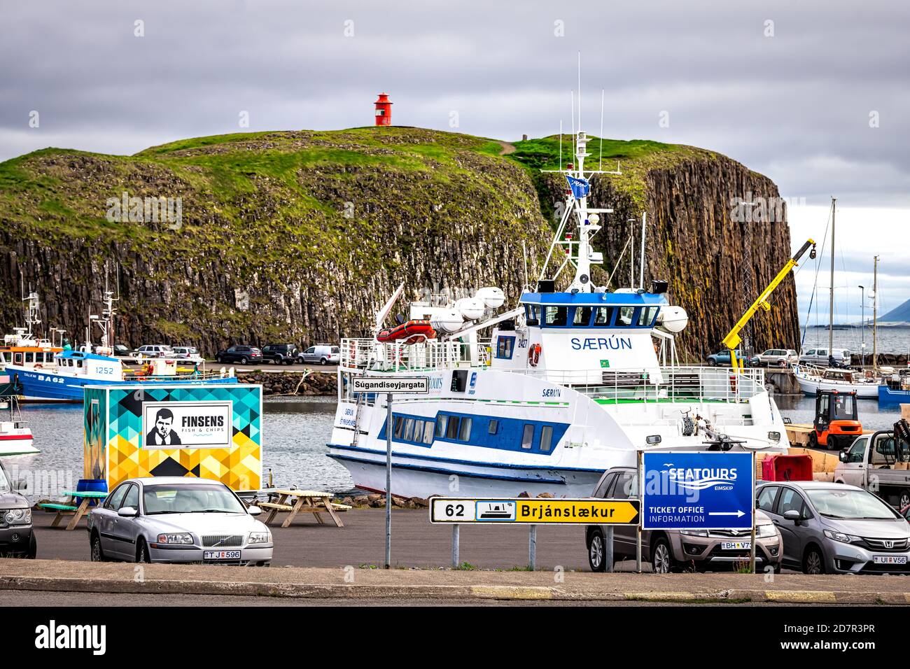 Stykkisholmur, Island - 18. Juni 2018: Stadt am bewölkten Tag kleines Fischerdorf auf Snaefellsnes Halbinsel mit Booten Tour Schiffe und Parkplatz mit Stockfoto