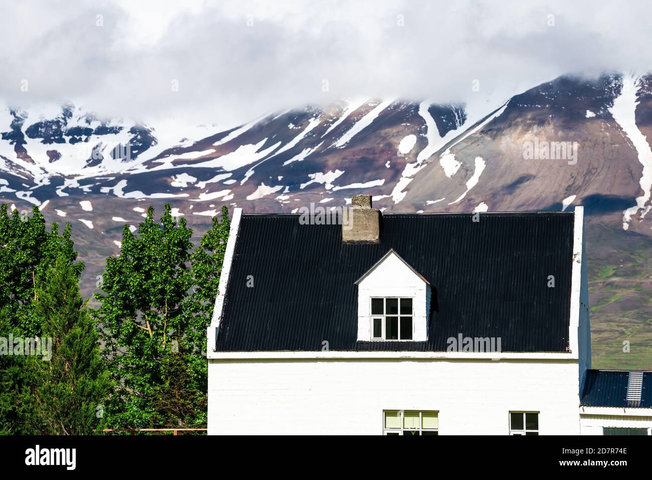 Blick auf Sulur bei Akureyri mit wolkenverhangendem Himmel und Nahaufnahme von Bauernhaus und schneebedeckten Bergen Stockfoto