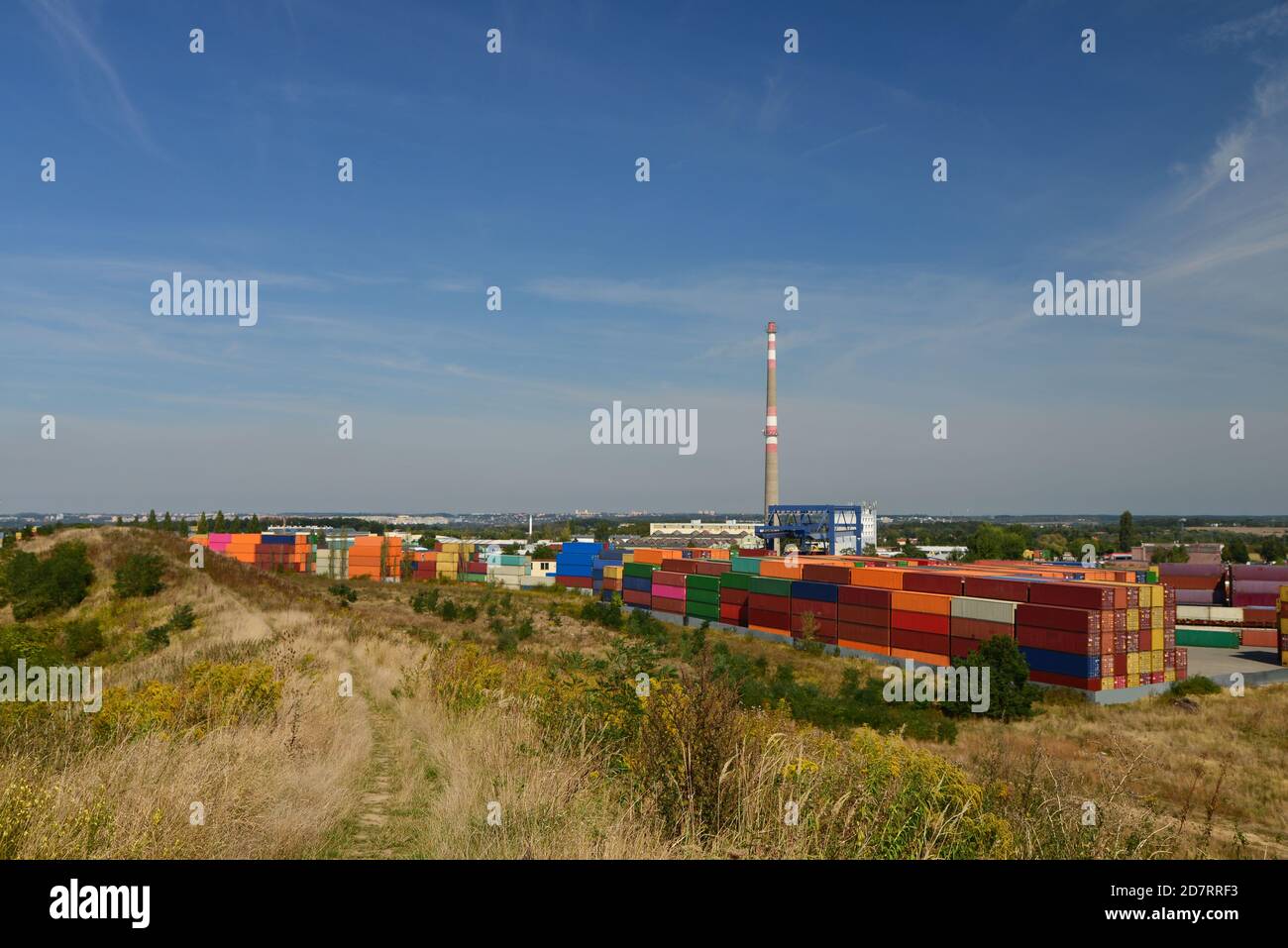 Draufsicht auf ein Container-Ladedock voller Stahlcontainer. Ein riesiges Außenlager mit einem hohen Betonkamin und großen Kranen. Blau Stockfoto