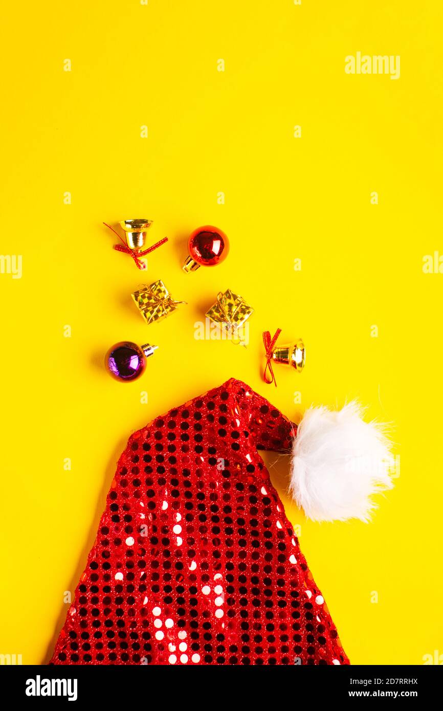 Weihnachtsmann Hut mit weihnachtskugeln, Geschenken und funkelnden Glocken auf gelbem Hintergrund. Stockfoto