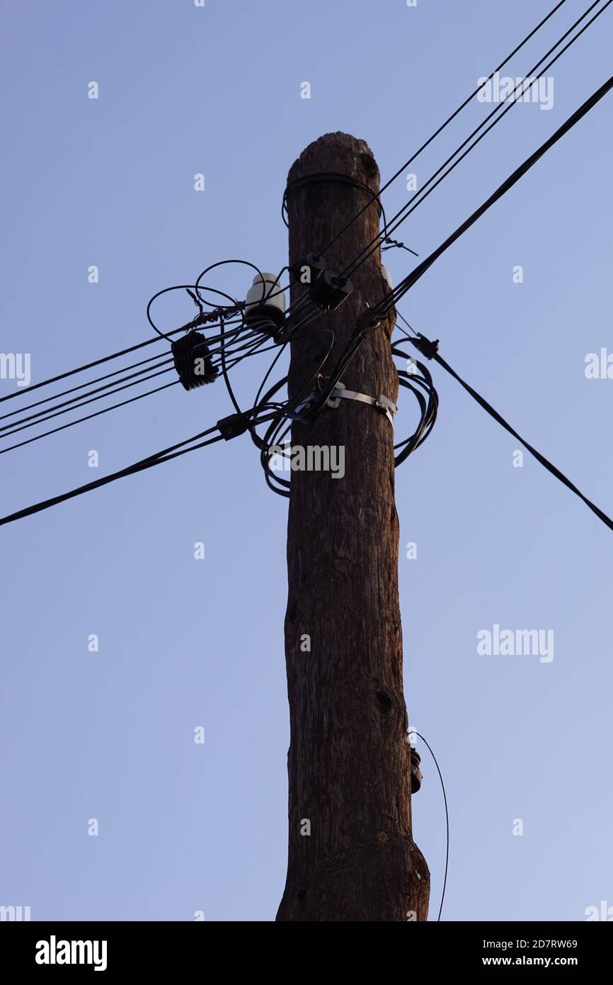 Alte hölzerne Säule mit Drähten auf dem blauen Himmel Hintergrund. Stockfoto