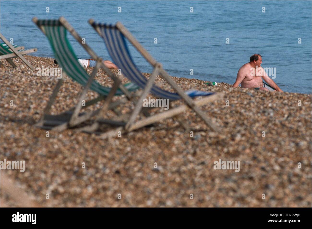 Urlauber und Touristen mit Liegestühlen am Kiesstrand in der Nähe des Palace Pier in Brighton. 20. Juli 1995. Foto: Neil Turner Stockfoto