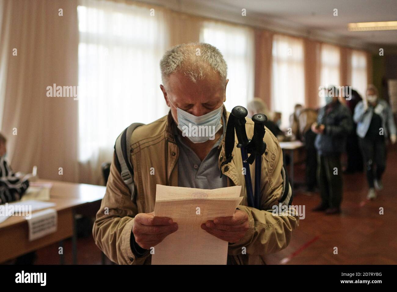 Non Exclusive: KIEW, UKRAINE - 25. OKTOBER 2020 - EIN Mann studiert einen Stimmzettel in einem Wahllokal während der Wahlen in der Ukraine 2020 in K Stockfoto