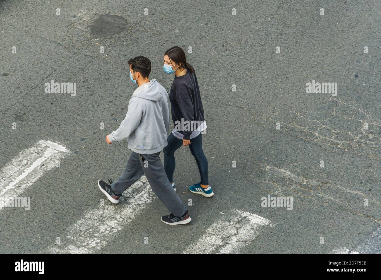 Menschen mit covid-19 Masken im Freien. Ein nicht identifiziertes Paar mit Gesichtsschutz geht auf einer Zebrakreuzung in Thessaloniki, Griechenland. Stockfoto