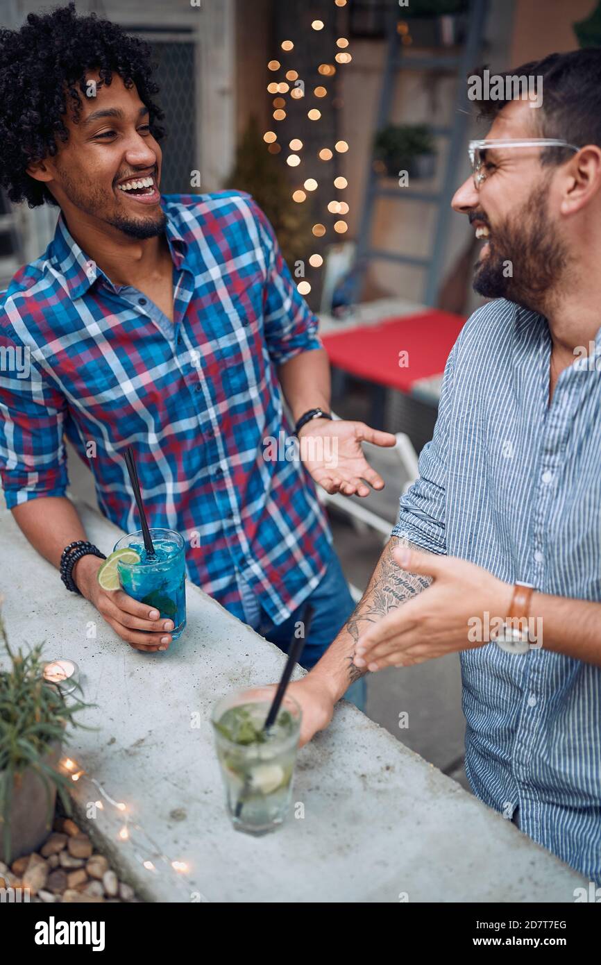 Männliche Freunde, die bei schönem Wetter im Hinterhof der Bar plaudern und trinken. Qualität Freundschaft Zeit zusammen Stockfoto