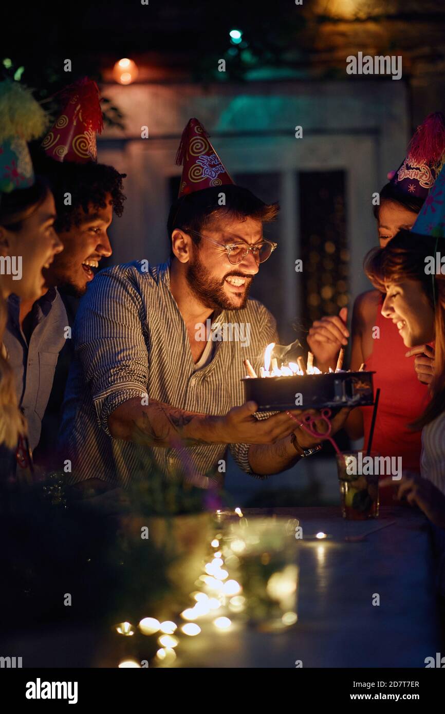 Eine Gruppe von fröhlichen Freunden aufgeregt über Kuchen auf der Open-Air-Geburtstagsparty an einem schönen Sommerabend. Qualität Freundschaft Zeit zusammen Stockfoto