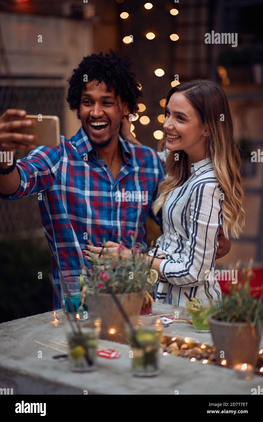 Glückliches Paar, das ein Selfie auf der Open-Air-Geburtstagsparty an einer schönen Sommerdämmerung macht. Qualität Freundschaft Zeit zusammen Stockfoto