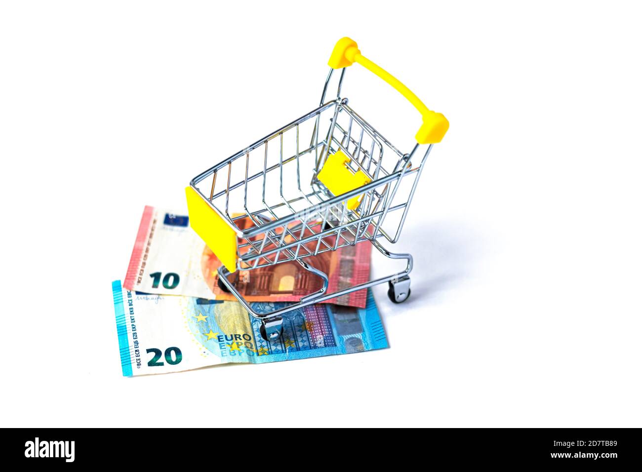Kleiner Warenkorb gefüllt mit Euro Cash auf weißem Hintergrund. 30 Euro in einem gelben Einkaufswagen. Konzept von Ausgaben und Shopping. Isoliert. Stockfoto
