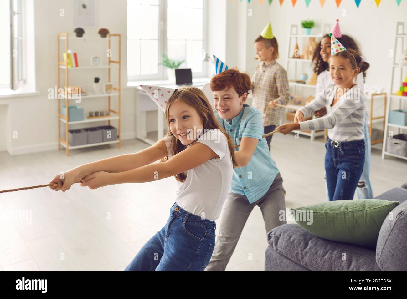 Glückliche Kinder spielen Tauziehen auf Spaß Party zu Hause oder Im Freizeitclub für Kinder Stockfoto