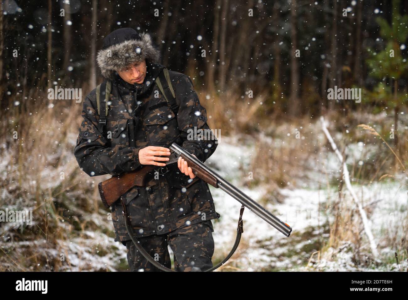 Hunter mit einer Waffe und einem Rucksack im Winter Wald Stockfoto