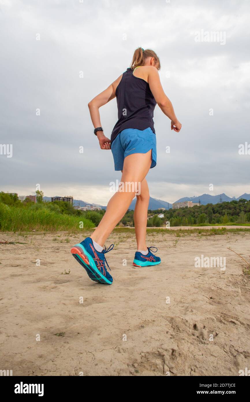 Athletische Frau, die sich vor ihrem morgendlichen Training auf der Waldbergstraße aufwärmt. Läufertraining im Freien, gesundes Lifestyle-Konzept. Stockfoto