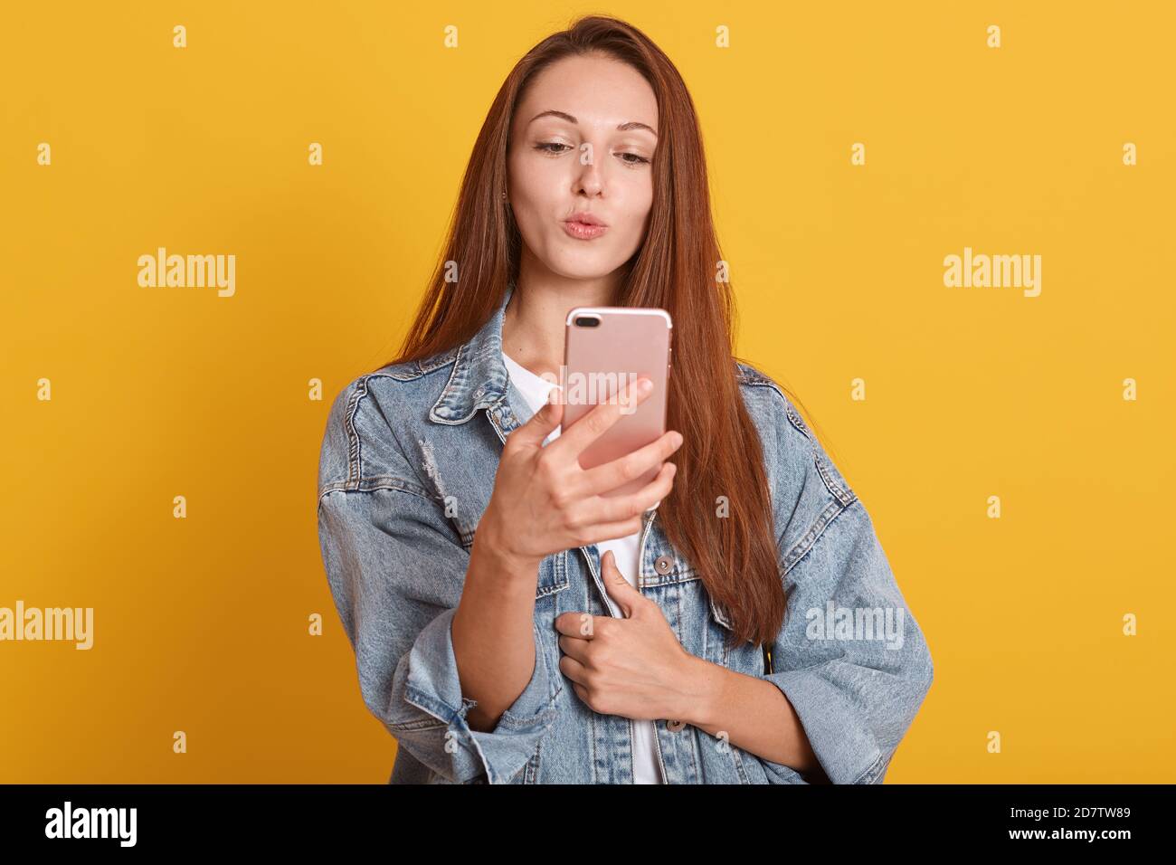 Bild der jungen Frau posiert für lustige Selfie, Kuss Geste, Blick auf die Kamera auf ihrem Handy, charmante Dame in modischen Denim Jack Stockfoto