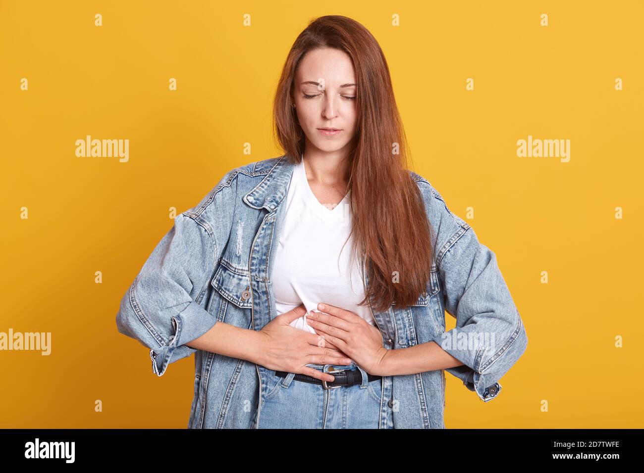 Indoor Studio Bild von verärgert nette junge Dame Schmerzen, halten beide Hände auf dem Bauch, Magenschmerzen, Schließen der Augen, mit unangenehmen fa Stockfoto