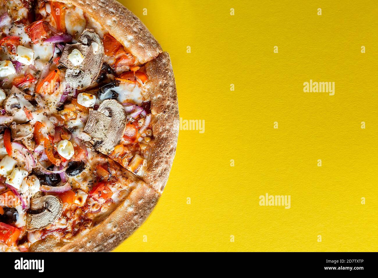 Eine halbe Pizza mit Gemüse ist auf einem hellgelben Hintergrund. Leerzeichen für Text. Der Blick von oben. Stockfoto