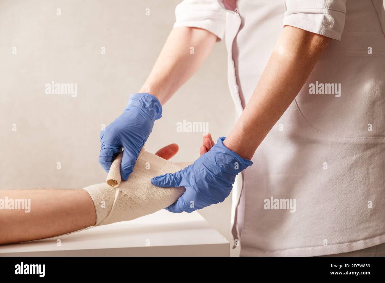 Der Arzt legt dem Handgelenk des Patienten eine elastische Bandage auf. Rehabilitation nach Verstauchung Stockfoto