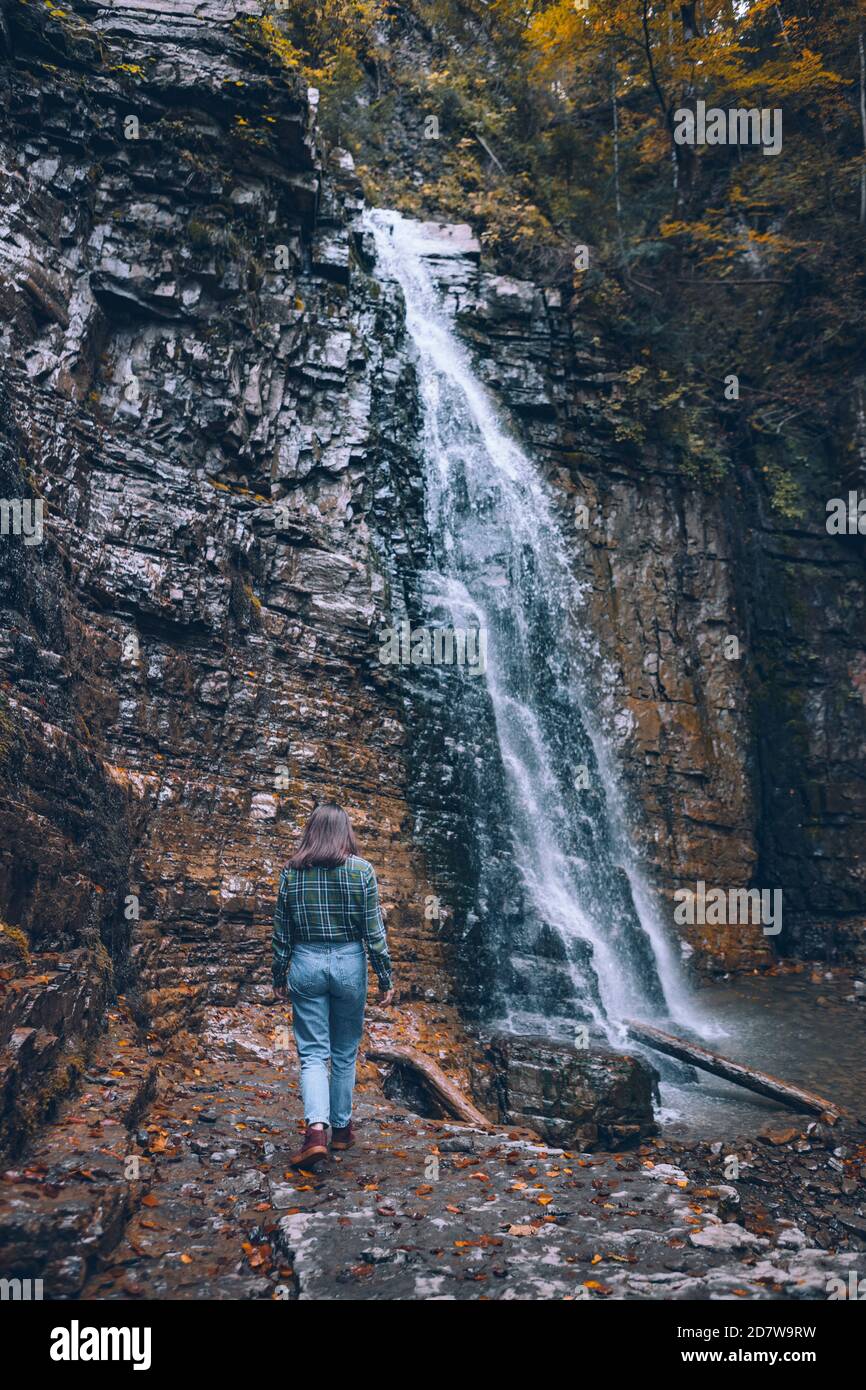 Frau in legerer Kleidung mit Blick auf den Wasserfall Stockfoto