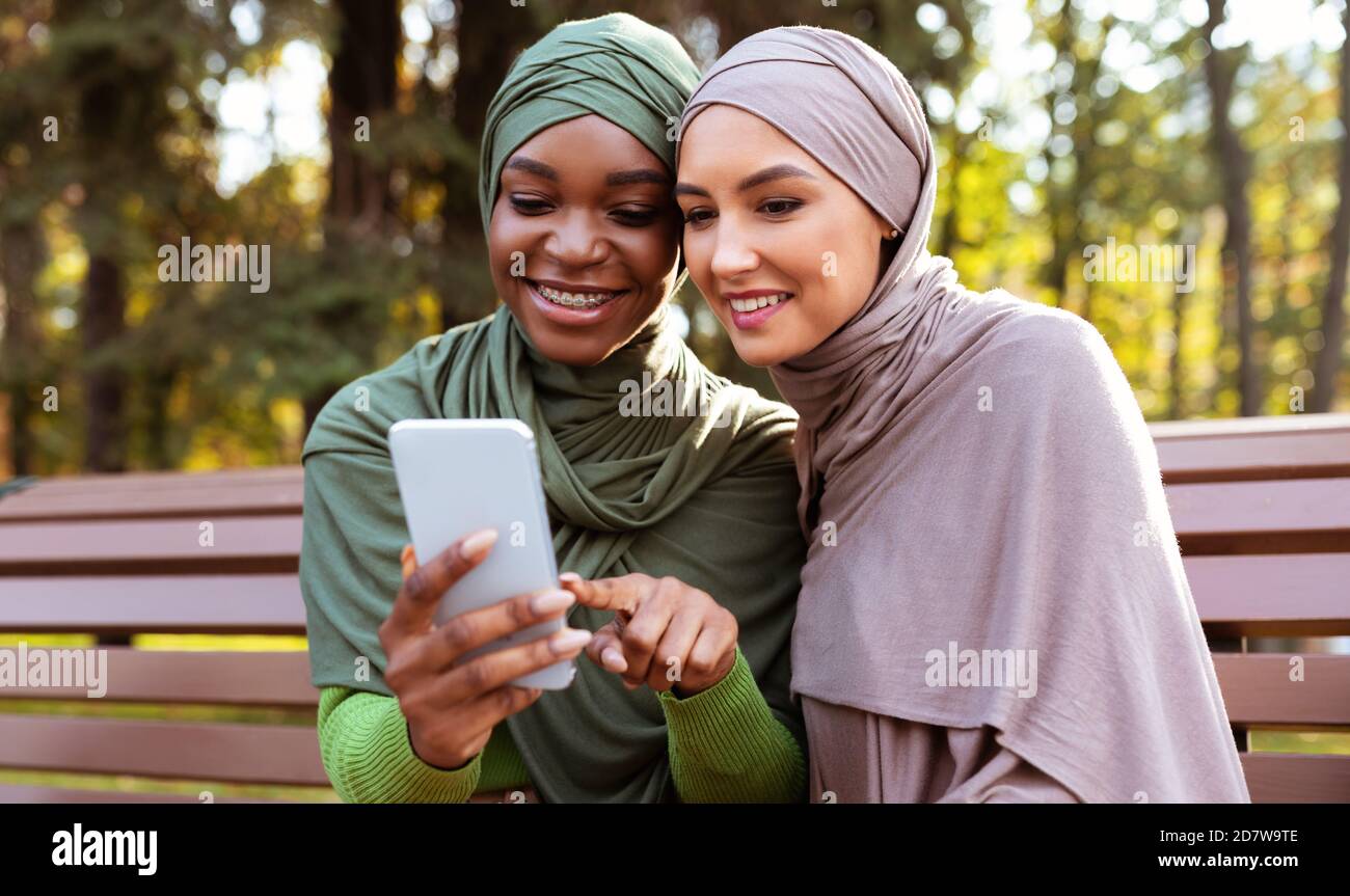 Moderne Muslimische Frau Empfehlen Smartphone Mobile App An Freunde Outdoor Stockfoto