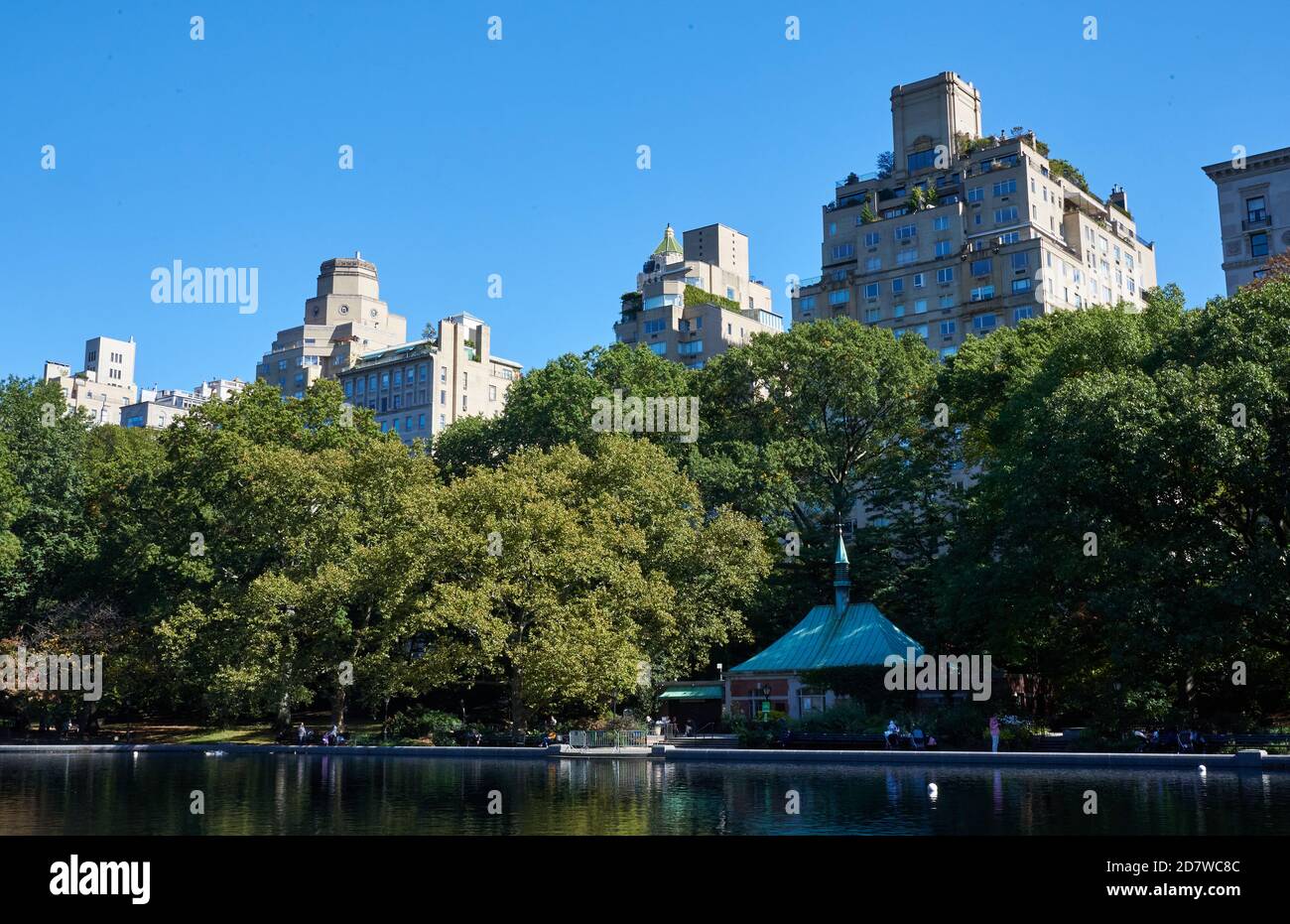 Conservatory Water ist ein Modellboot Teich im Central Park in Manhattan, New York City. Hinter den Bäumen sind Wohngebäude auf der Fifth Avenue Stockfoto