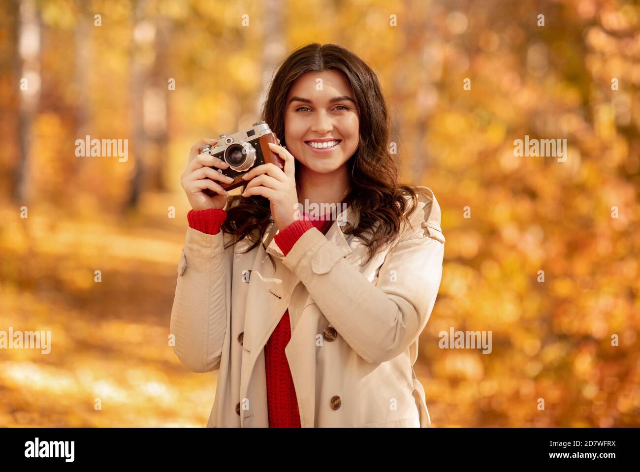 Portrait von schönen weiblichen Fotografen mit Retro-Kamera posiert und Lächelnd im gelben Herbstpark Stockfoto