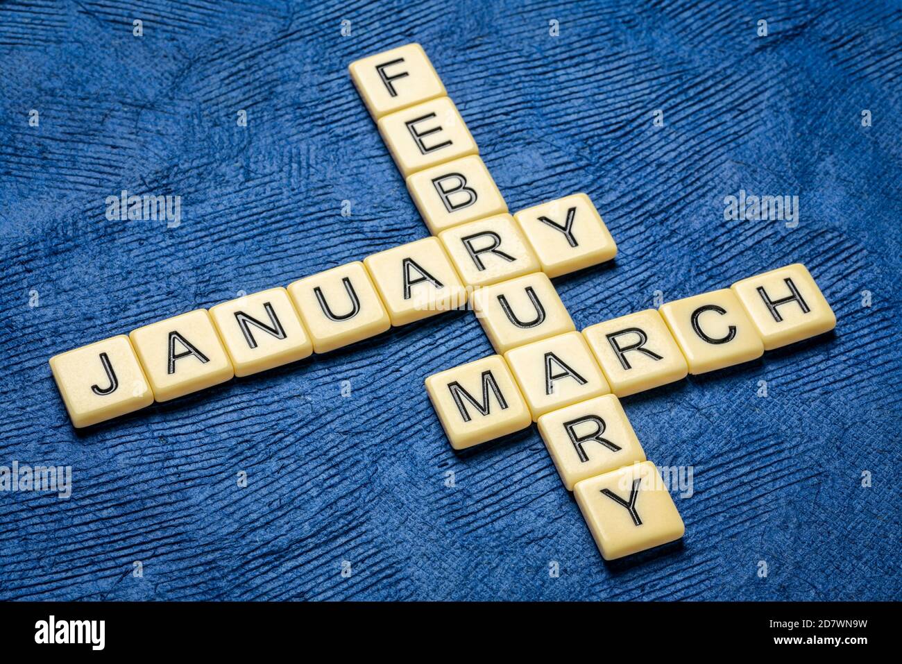 Januar, Februar und März Kreuzworträtsel in Elfenbein Buchstaben Fliesen gegen strukturierte handgefertigte Rinde Papier, Kalender-Konzept Stockfoto