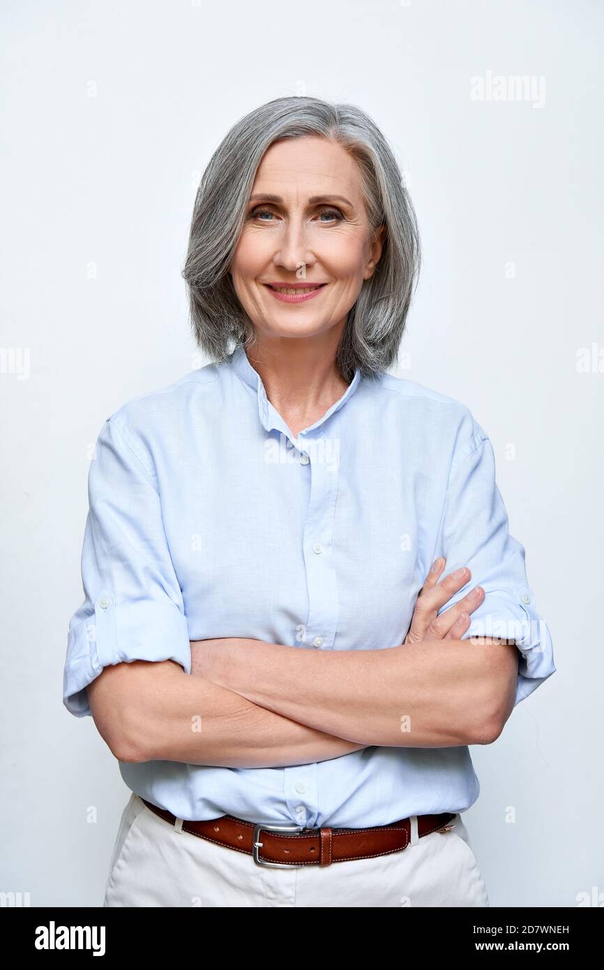 Selbstbewusst lächelnde reife Frau auf grauem Hintergrund, vertikales Porträt. Stockfoto