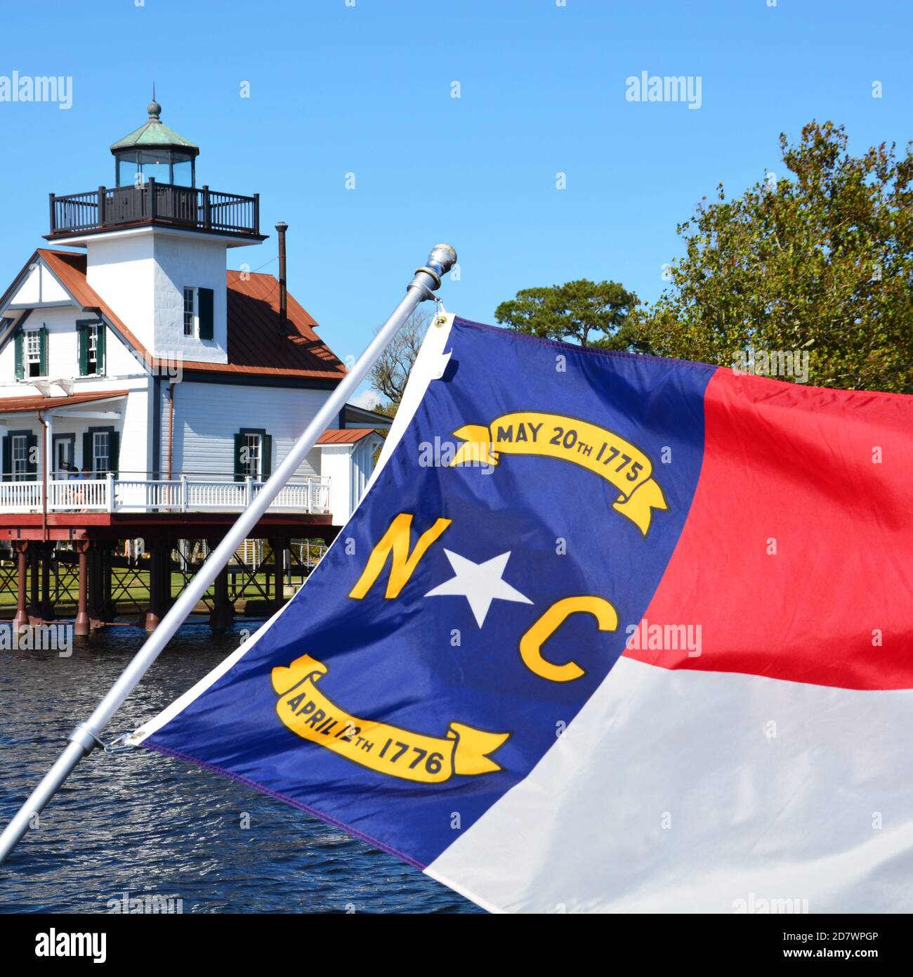 Die Flagge von North Carolina, die vor einem Leuchtturm fliegt. Stockfoto