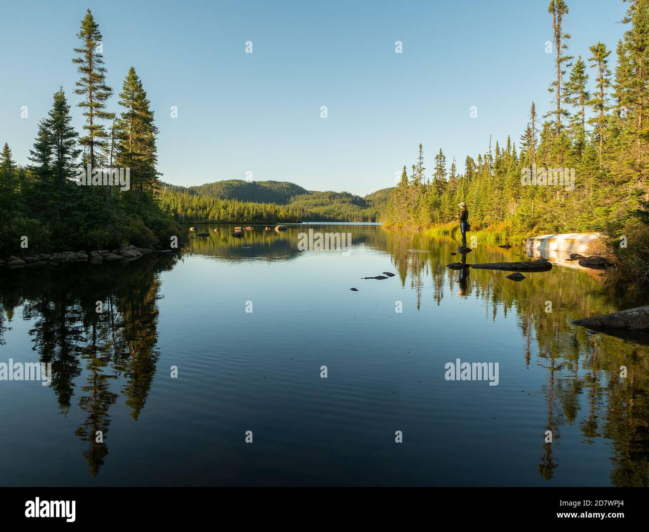 Frau, die auf einem Felsen steht und in einem See im Norden Quebecs angeln Stockfoto