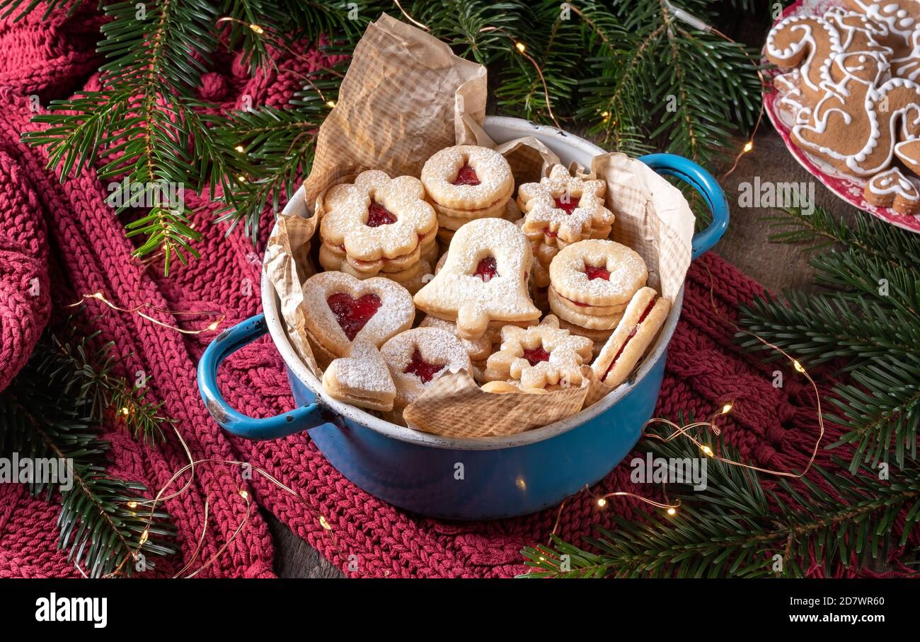 Linzer Weihnachtsplätzchen gefüllt mit Marmelade, mit Tannenzweigen und Lebkuchen im Hintergrund Stockfoto