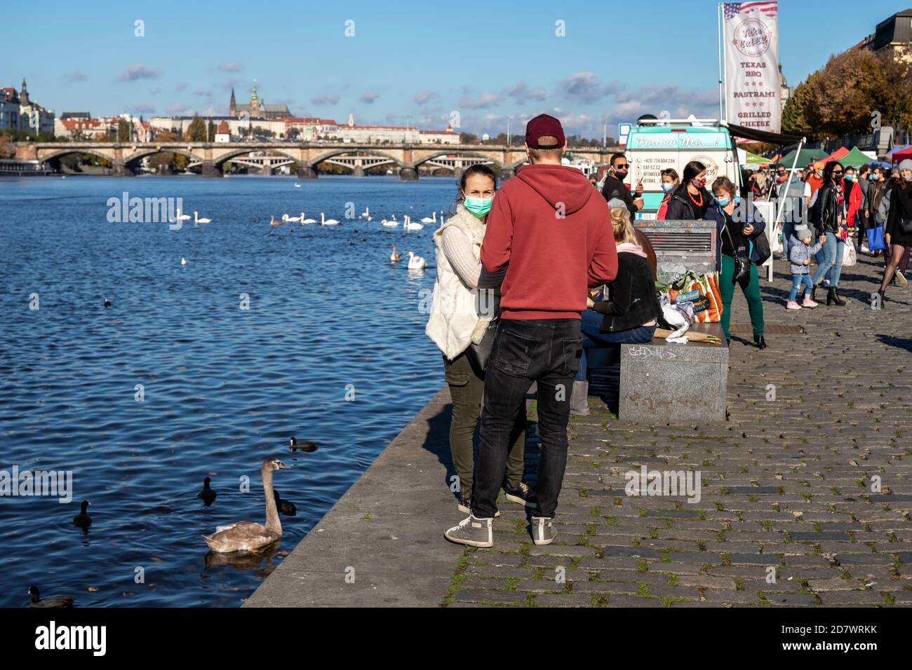 PRAG, TSCHECHISCHE REPUBLIK - 24. OKTOBER 2020: Menschen mit Gesichtsmasken füttern Schwan auf dem Bauernmarkt Naplavka während der zweiten Welle des Coronavirus Stockfoto