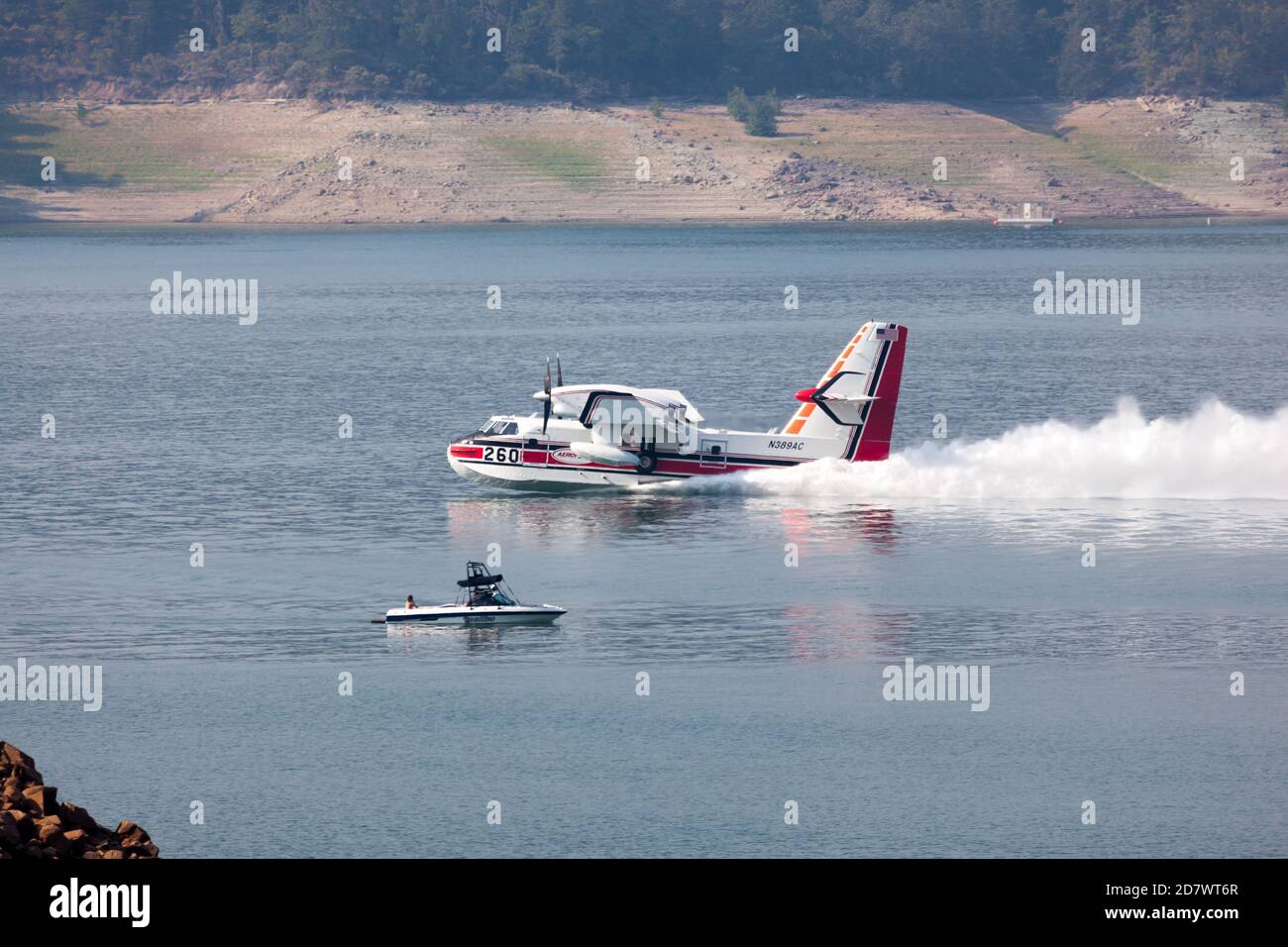 Lost Creek Lake in der Nähe von Prospect, Oregon / USA - 7. September 2014: Ein kleines Löschflugzeug überfliegt die Seenoberfläche, um Wasser in Lost Creek aufzuschöpfen Stockfoto