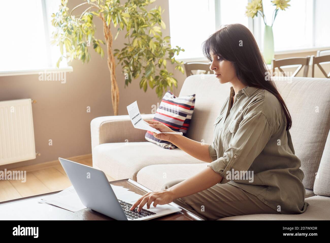 Junge indische Frau hält Rechnung mit Laptop Zahlung Rechnung online zu Hause. Stockfoto