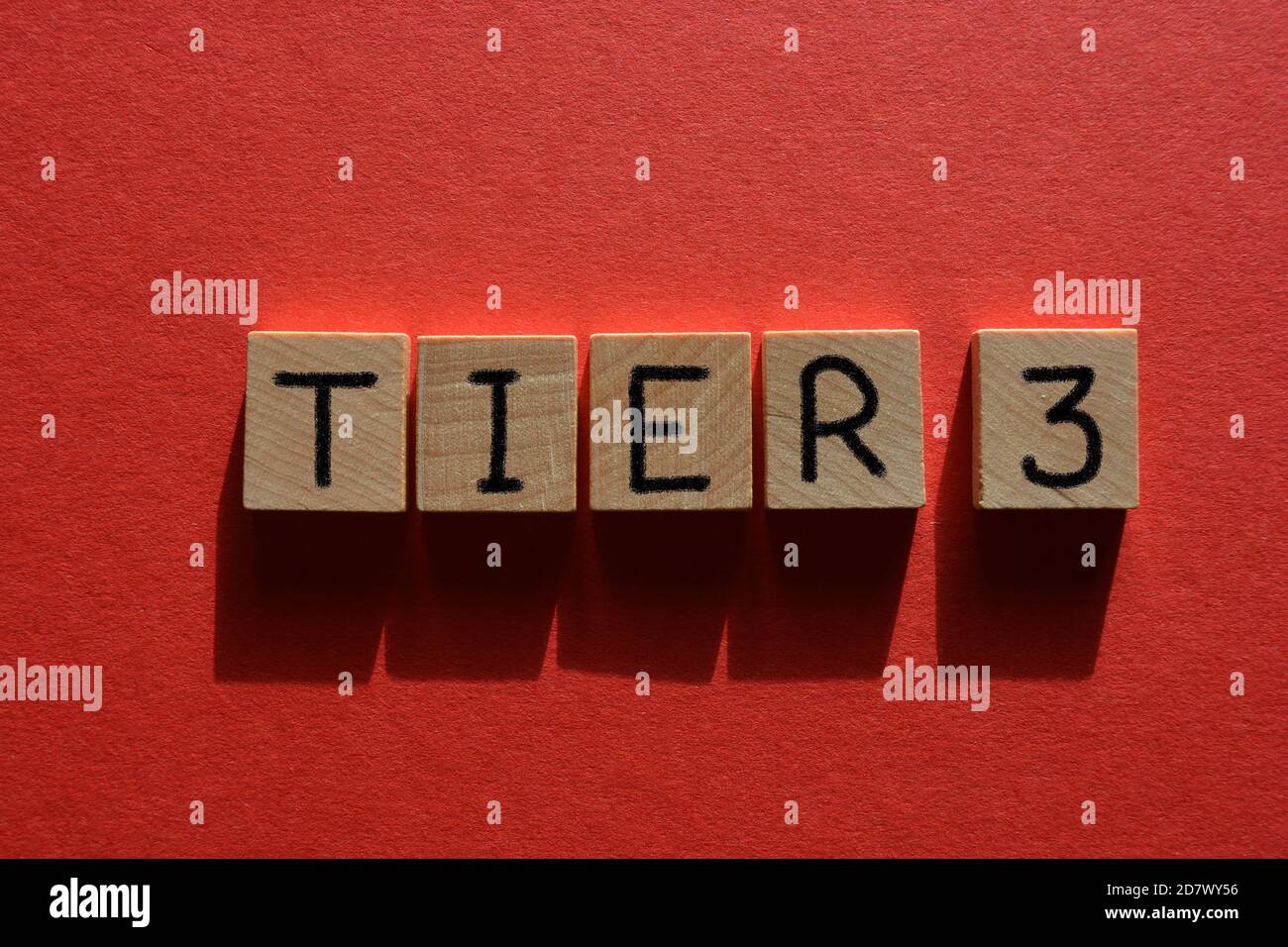 Tier 3, Coronavirus Alarmstufen, Wort in Holzbuchstaben isoliert auf rotem Hintergrund Stockfoto